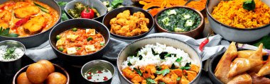 Hint mutfağı tabakları. Köri, tereyağlı tavuk, pilav, mercimek, paneer, samosa, baharatlar. Koyu arkaplanda Hint yemeği olan kâseler ve tabaklar. 