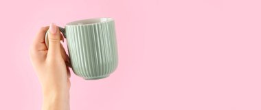 Kollarını kaldır ve pembe arka planda kahve fincanı tut.. 