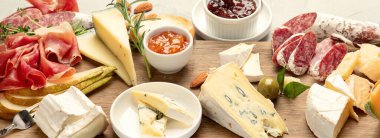 Hafif arka planda peynir çeşitleri. Gurme aperatifleri tepside. İtalyan yemeği konsepti. Üst Manzara. Panorama.