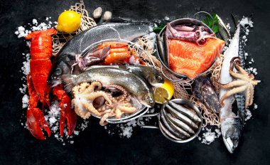 Taze balık ve deniz ürünleri çeşitleri kara arka planda, balık pazarında. Sağlıklı beslenme konsepti. 