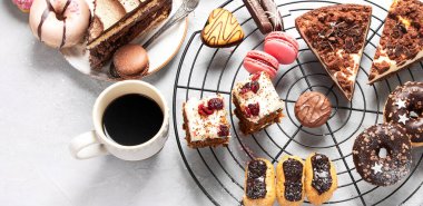 Kurabiye, çörek, kek ve kahve fincanlarıyla dolu bir masa. Üst görünüm.