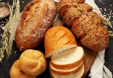 Koyu arkaplanda taze ekmek çeşitleri. Taze ev yapımı hamur işi. Üst görünüm.