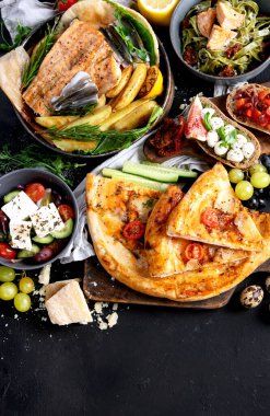 Çeşitli Akdeniz yemekleri - balık, deniz ürünleri, soslar, makarna, atıştırmalıklar, siyah arka planda pizza. Üst Manzara. Boşluğu kopyala.