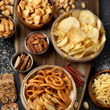 Karanlık arka planda tuzlu atıştırmalıklar. Parti yemeği konsepti. Üst görünüm.