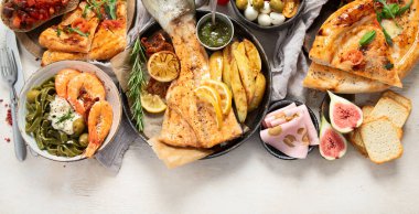 Tabak ve yemek üzerinde İtalyan yemekleriyle dolu bir masa pizza, makarna, salam, parmesan, zeytin, beyaz arka planda ekmek çubukları. Üst Manzara. Boşluğu kopyala.