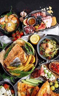Çeşitli Akdeniz yemekleri - balık, deniz ürünleri, soslar, makarna, atıştırmalıklar, siyah arka planda pizza. Üst görünüm. 