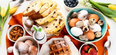 Bayramlık Paskalya sofrası. Doğal renkli yumurtalar ve bahar çiçekleri kırsal bileşimi. Üst görünüm.