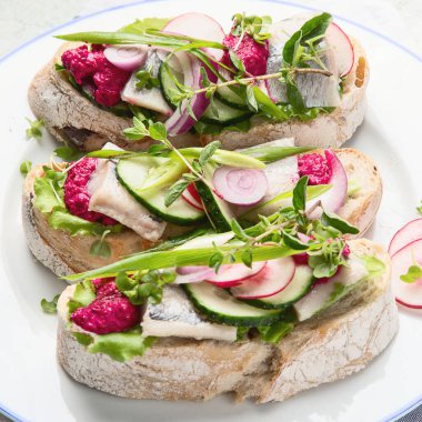 Smorrebrod, geleneksel Danimarka açık yüzlü sandviçler gri arka planda bir tabakta. Üst görünüm.