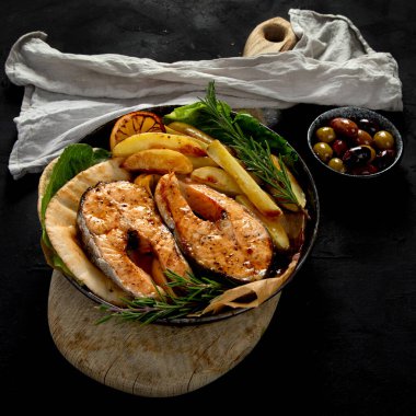 Pişmiş somon bifteği ve kızarmış patatesler siyah arka planda servis ediliyor. Sağlıklı beslenme. Üst görünüm.