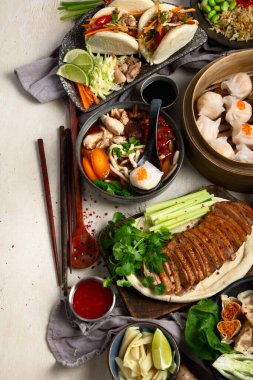 Koyu arkaplanda Çin yemekleri: tatlı ördek, çorba, buharda pişmiş çörekler, bambu buharlı buhar tenceresi, salata, pilav, sos. Asya usulü ziyafet, en iyi manzara. Boşluğu kopyala.