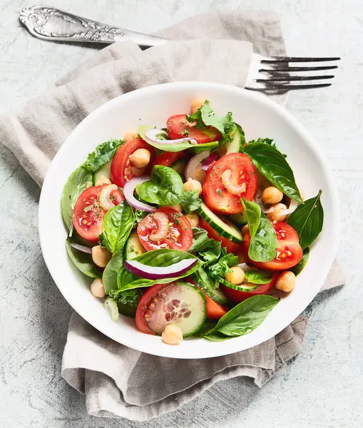 Gri arka planda sağlıklı sebze salatası. Sebze aperatifi. Vejetaryen ve vejetaryen menüsü. Temiz ve detoks yeme konsepti. Üst görünüm. 