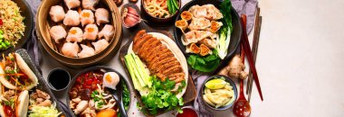 Koyu arkaplanda Çin yemekleri: tatlı ördek, çorba, buharda pişmiş çörekler, bambu buharlı buhar tenceresi, salata, pilav, sos. Asya usulü ziyafet, en iyi manzara. Kopyalama alanı olan Panorama.