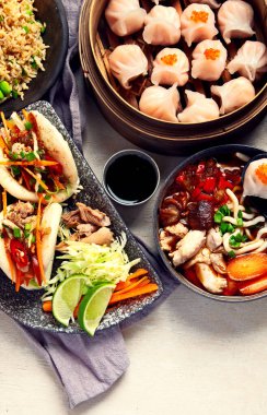 Koyu arkaplanda Çin yemekleri: tatlı ördek, çorba, buharda pişmiş çörekler, bambu buharlı buhar tenceresi, salata, pilav, sos. Asya usulü ziyafet, en iyi manzara. Boşluğu kopyala.