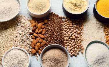 Çeşitli glütensiz un - nohut, pilav, karabuğday, kinoa, badem, mısır, arka planda yulaf ezmesi. Üst görünüm.