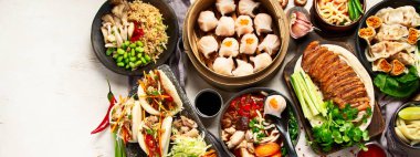 Koyu arkaplanda Çin yemekleri: tatlı ördek, çorba, buharda pişmiş çörekler, bambu buharlı buhar tenceresi, salata, pilav, sos. Asya usulü ziyafet, en iyi manzara. Kopyalama alanı olan Panorama.