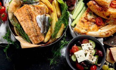 Çeşitli Akdeniz yemekleri - balık, deniz ürünleri, soslar, makarna, atıştırmalıklar, siyah arka planda pizza. Üst Manzara. Boşluğu kopyala.