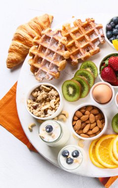 Yumurta, böğürtlen, yoğurt, waffle ve kruvasanla kahvaltı masası. Üst Manzara. Kahvaltı tabakları çeşitleri. Kopyalama alanı olan Panorama.
