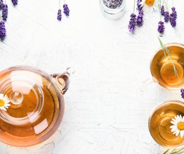 Beyaz arka planda lavanta ve papatya çiçekli sağlıklı bitki çayı. Üst görünüm.