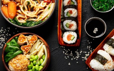 Çeşitli gurme Japon yemekleri. Suşi, rulo ekmek, siyah arka planda çorba ve pirinç. Üst görünüm.