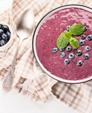 Beyaz arka planda sağlıklı kahvaltı için taze yaban mersinli meyve suyu kasesi. Üst Manzara. Sapı kopyala.