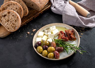 Koyu arkaplanda zeytin, zeytinyağı ve ciabatta ekmeği. Üst görünüm.