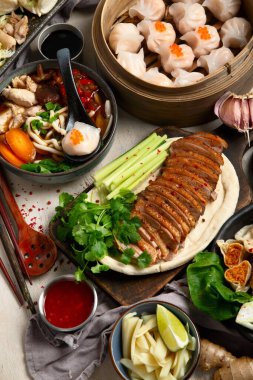 Koyu arkaplanda Çin yemekleri: tatlı ördek, çorba, buharda pişmiş çörekler, bambu buharlı buhar tenceresi, salata, pilav, sos. Asya tarzı ziyafet, üst görünüm. 