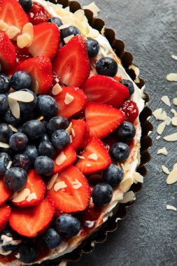 Gri arka planda taze çilek ve böğürtlenli lezzetli tart. Üst görünüm.