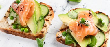 Avokado ve somon ile sağlıklı bahar tostları. Sağlıklı kahvaltı konsepti. Üst görünüm.