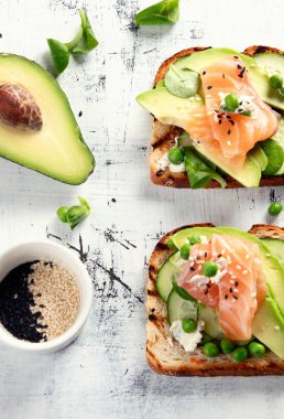 Avokado ve somon ile sağlıklı bahar tostları. Sağlıklı kahvaltı konsepti. Üst görünüm.