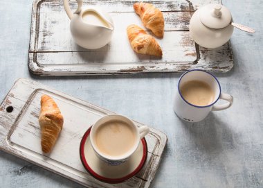 Gri arka planda bir fincan kahve ve kruvasanla kahvaltı. Üst görünüm.