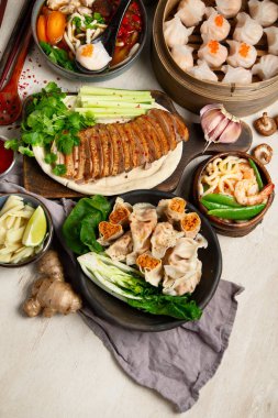 Koyu arkaplanda Çin yemekleri: tatlı ördek, çorba, buharda pişmiş çörekler, bambu buharlı buhar tenceresi, salata, pilav, sos. Asya usulü ziyafet, en iyi manzara. Boşluğu kopyala.