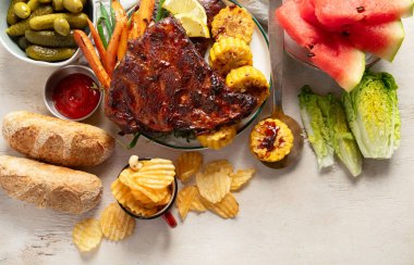 Sebzeli barbekü kaburgası, sos, kavrulmuş mısır ve beyaz arka planda karpuz. Üst görünüm.