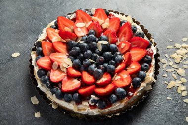 Gri arka planda taze çilek ve böğürtlenli lezzetli tart. Üst görünüm.