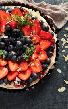 Gri arka planda taze çilek ve böğürtlenli lezzetli tart. Üst görünüm.