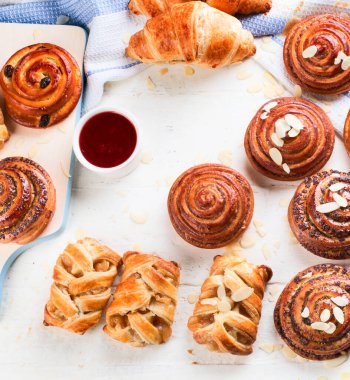 Beyaz arka planda çeşitli lezzetli, taze hamur işleri, çörekler ve kruvasanlar. Üst görünüm.