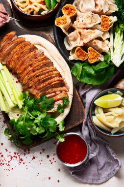 Koyu arkaplanda Çin yemekleri: tatlı ördek, çorba, buharda pişmiş çörekler, bambu buharlı buhar tenceresi, salata, pilav, sos. Asya tarzı ziyafet, üst görünüm. 