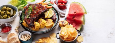 Sebzeli barbekü kaburgası, sos, kavrulmuş mısır ve beyaz arka planda karpuz. Üst Manzara. Kopyalama alanı olan Panorama