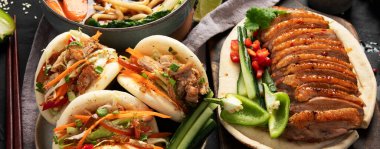 Koyu arkaplanda Çin yemekleri: tatlı ve ekşi ördek, erişte çorbası, buğulanmış çörekler. Asya tarzı ziyafet ya da açık büfe, üst manzara. Panorama