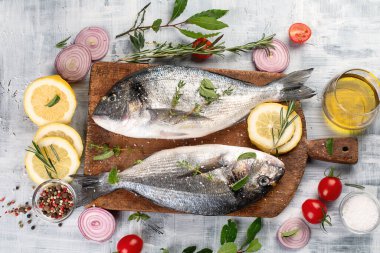 Gri arka planda baharatlı çiğ dorado balığı. Üst görünüm.