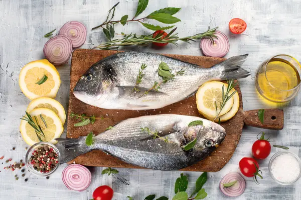 Gri arka planda baharatlı çiğ dorado balığı. Üst görünüm.