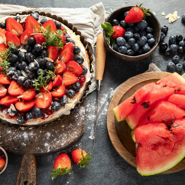 Gri arka planda taze çilek ve böğürtlenli lezzetli tart. Üst görünüm.