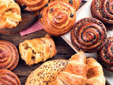 Ekmek, çörek, kruvasan. Ahşap arka planda fırın malzemeleri. Kahvaltı konsepti. Üst Manzara. Panorama.