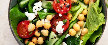 Domates, salatalık, salata, nohut ve peynirli vejetaryen nohut salatası hafif bir arka planda. Sağlıklı bir yaşam tarzı. Üst manzara, panorama.