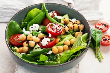 Domates, salatalık, salata, nohut ve peynirli vejetaryen nohut salatası hafif bir arka planda. Sağlıklı bir yaşam tarzı. Üst yaşam