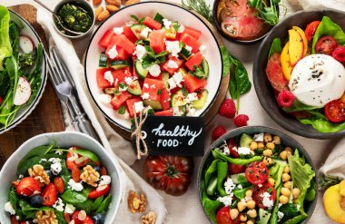 Çilekli çeşitli yaz salataları, otlar. Hafif arkaplanlı sağlıklı salata, şeftali, burrata, yabanmersini ve ceviz. Sağlıklı yemek için taze yararlı yemek. Üst görünüm.