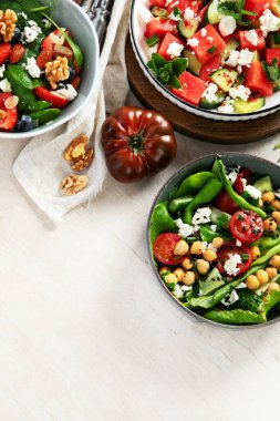 Çilekli çeşitli yaz salataları, otlar. Hafif arkaplanlı sağlıklı salata, şeftali, burrata, yabanmersini ve ceviz. Sağlıklı yemek için taze yararlı yemek. Üst Manzara. Boşluğu kopyala.