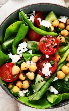 Domates, salatalık, salata, nohut ve peynirli vejetaryen nohut salatası hafif bir arka planda. Sağlıklı bir yaşam tarzı. Üst yaşam