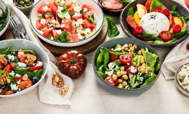 Çilekli çeşitli yaz salataları, otlar. Hafif arkaplanlı sağlıklı salata, şeftali, burrata, yabanmersini ve ceviz. Üst görünüm, alanı kopyala.