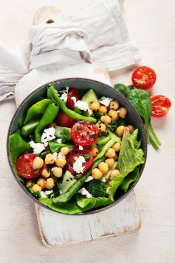 Domates, salatalık, salata, nohut ve peynirli vejetaryen nohut salatası hafif bir arka planda. Sağlıklı bir yaşam tarzı. Üst yaşam