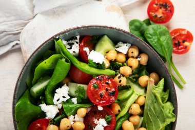 Domates, salatalık, salata, nohut ve peynirli vejetaryen nohut salatası hafif bir arka planda. Sağlıklı bir yaşam tarzı. Üst yaşam